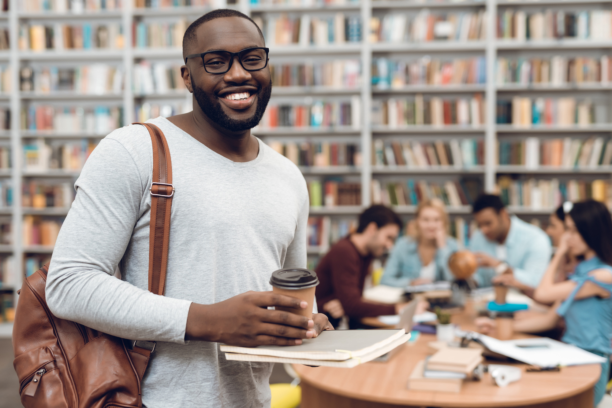 3656309 Group of ethnic multicultural students in library. Black guy with notes and coffee